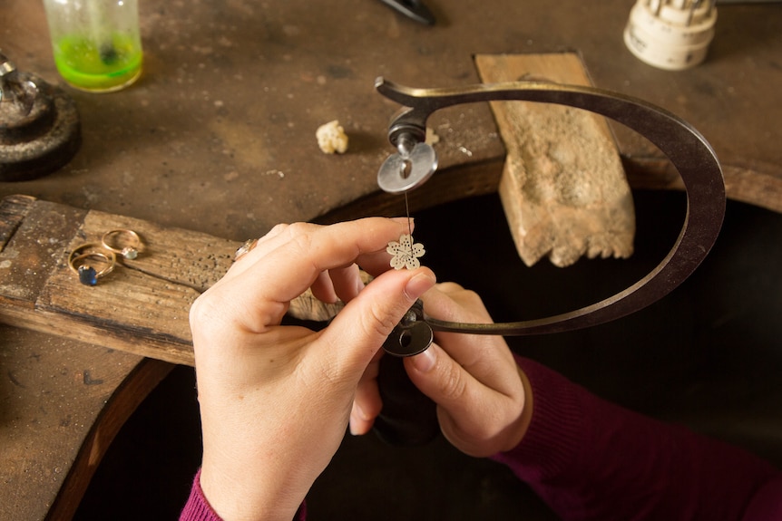 Jeweller works on a piece using a rounded jeweller's saw.