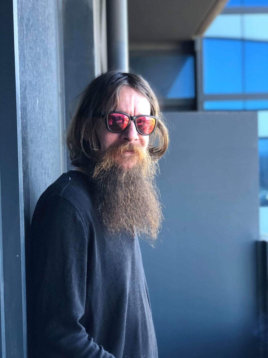 Shaun a tenant in Melbourne has a large beard and red-tinted sunglasses on.