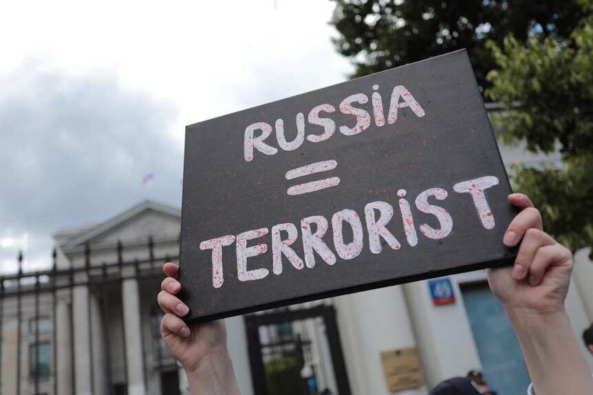 People hold banners in an anti-Russian demonstration outside the Russian embassy.