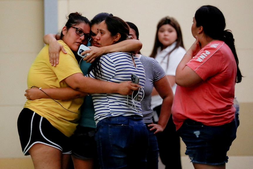 People hug each other outside a building.