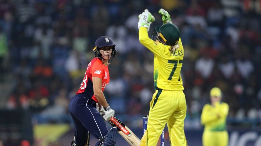 Alyssa Healy, seen from behind raises her hands in frustration as an England batter looks on.