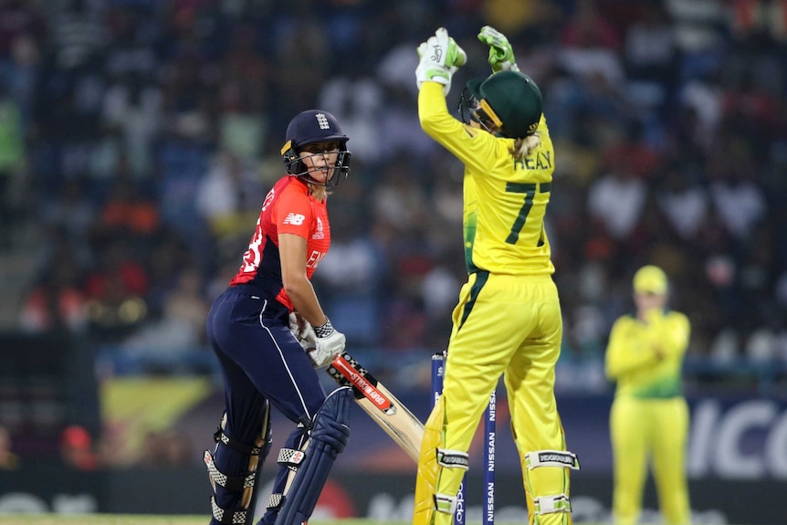 Alyssa Healy, seen from behind raises her hands in frustration as an England batter looks on.
