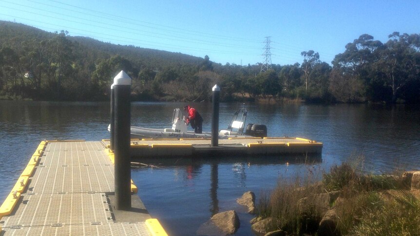 A police officer ties up a boat at a jetty near New Norfolk on the River Derwent.
