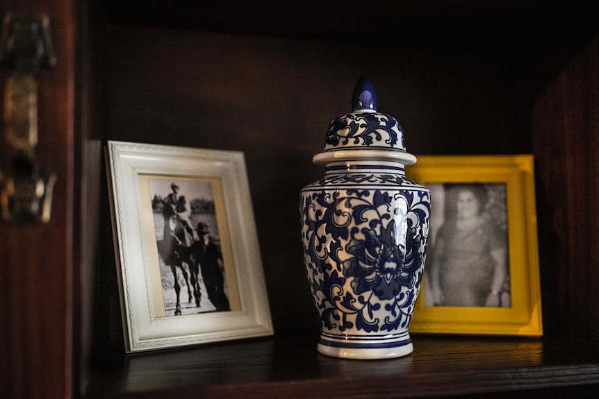 Two photos and a vase on a shelf.