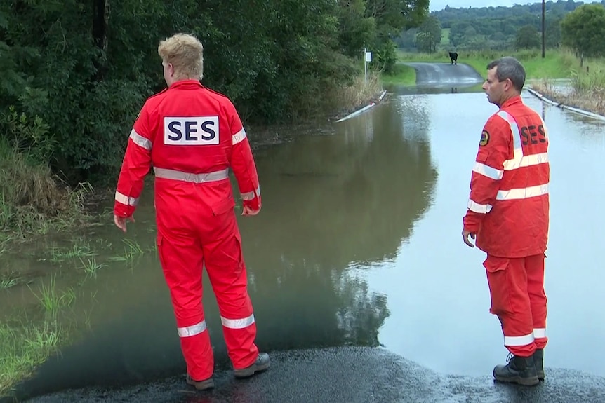 two es workers stand near a flooded road after a major weather event across nsw