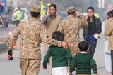 Soldier escorts schoolchildren from the Army Public School