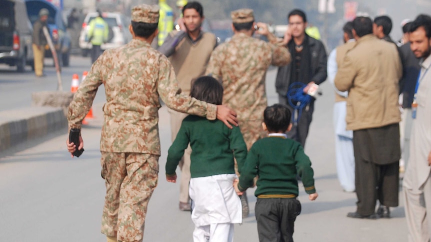 Soldier escorts schoolchildren from the Army Public School
