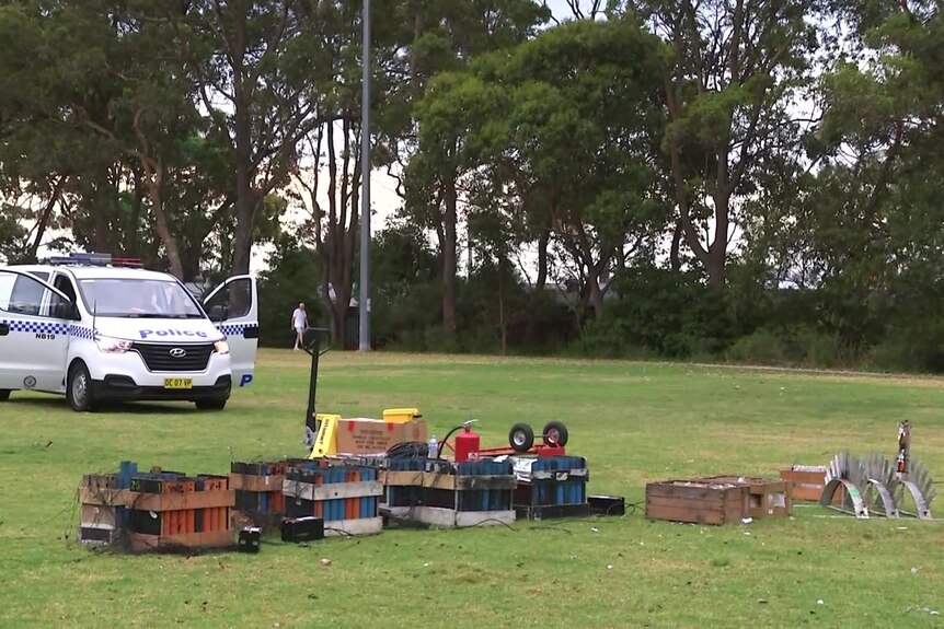 A police van next to boxes of spent fireworks in a park