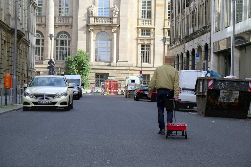 A man walking a trailer down a street