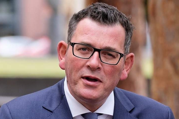 Daniel Andrews, dressed in a blue suit, holds a press briefing outdoors.