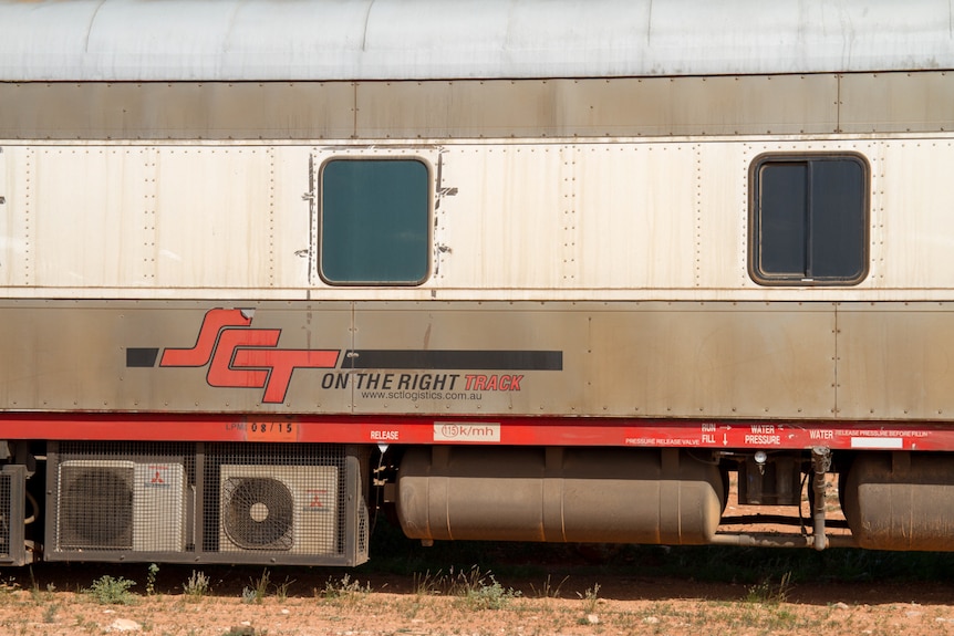 A train car off the tracks, sitting in the desert.