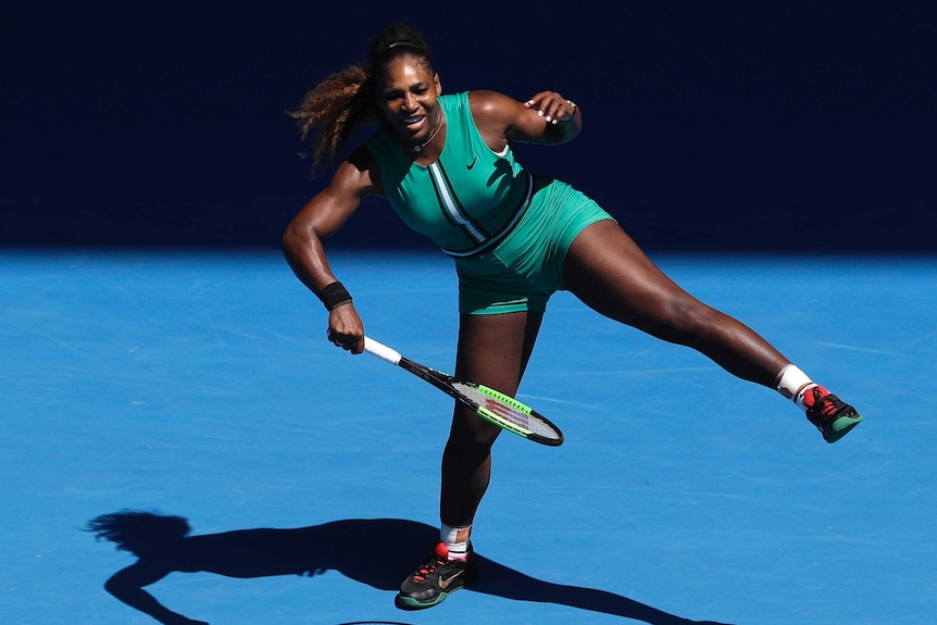 Serena Williams plays an awkward forehand while standing on one leg with a pained look on her face at the Australian Open.