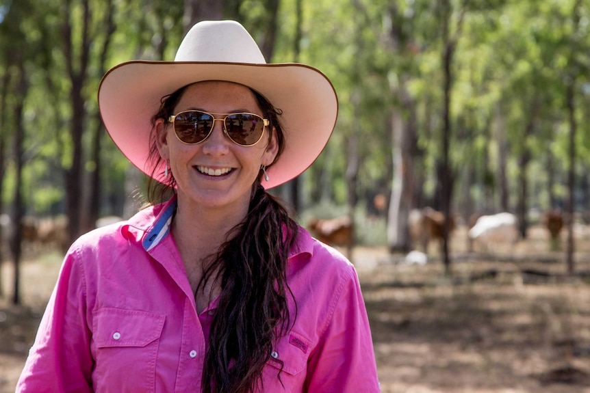 A profile picture of Alice Mabin. She is wearing a pink, collared shirt, an Akubra, sunglasses and brown, long hair.