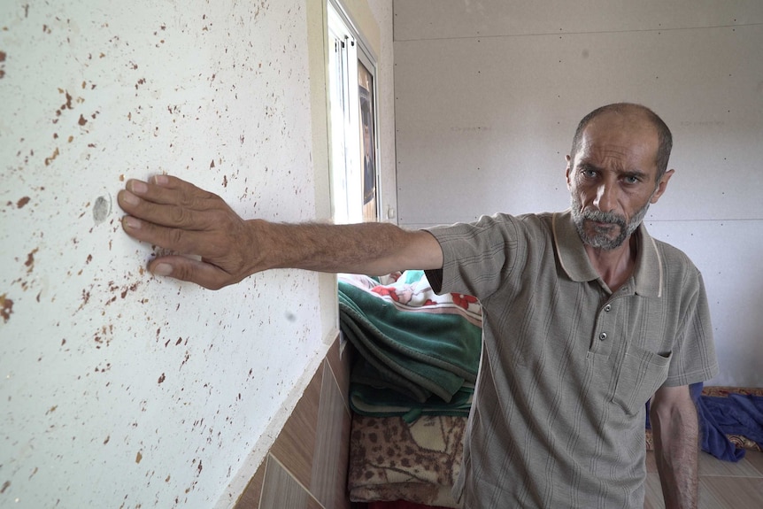 Ali Yusef Jabarin gestures to a hole Israeli soldiers drilled into the wall of his house.