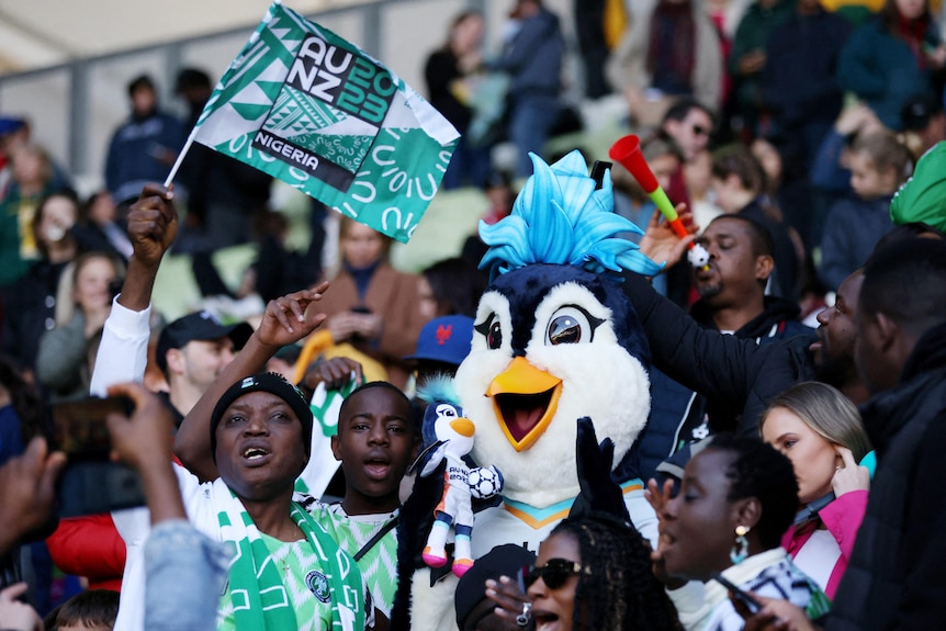 A penguin mascot is in a football crowd.