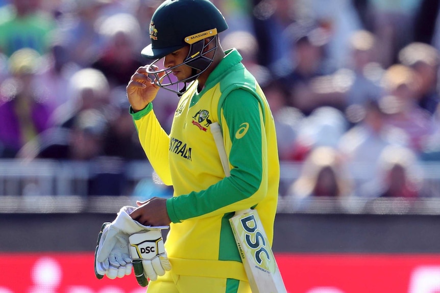 Usman Khawaja walks off holding his gloves in his hand