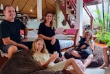 A man, a woman and three children lounge around in a living room 