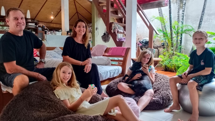 A man, a woman and three children lounge around in a living room 