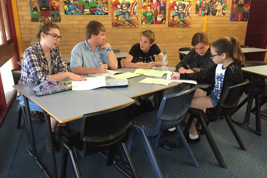 Students from the North Coast debating team sit at a table and discuss debating ideas.