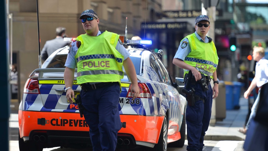 Dwóch policjantów stojących obok samochodu policyjnego