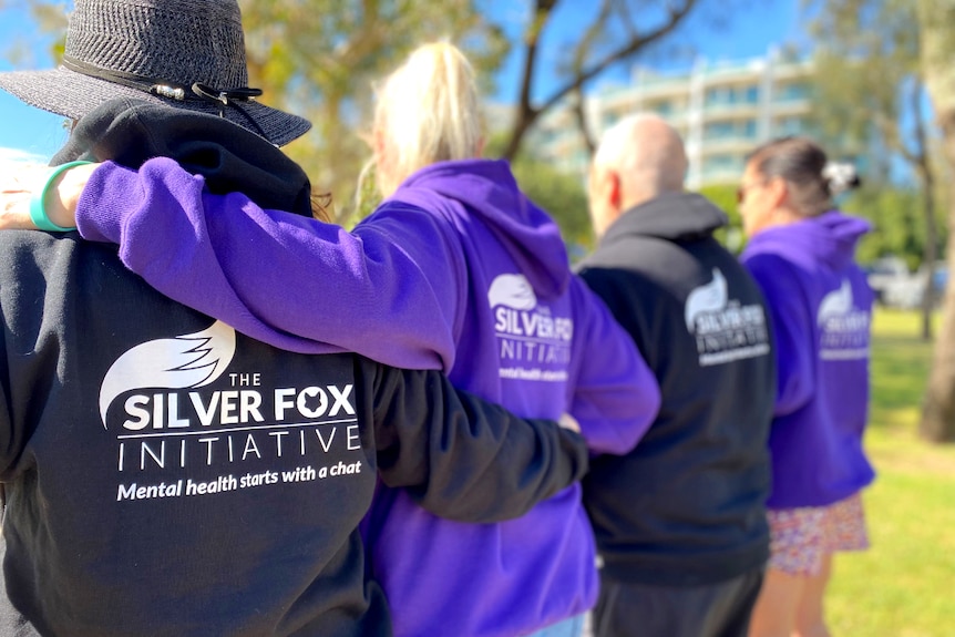 Four people standing with their backs to the camera wearing shirts that say silver fox initiative