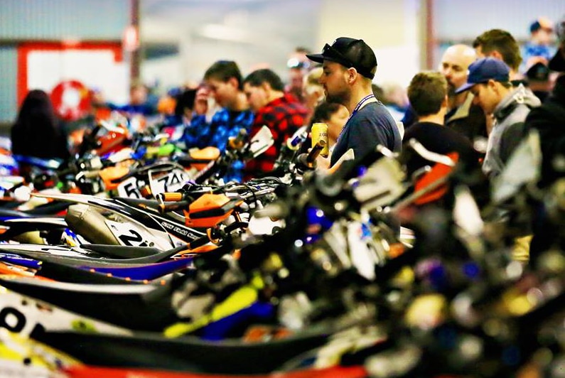 Competitors and spectators look over the bikes during scrutineering at a Finke Desert Race event.