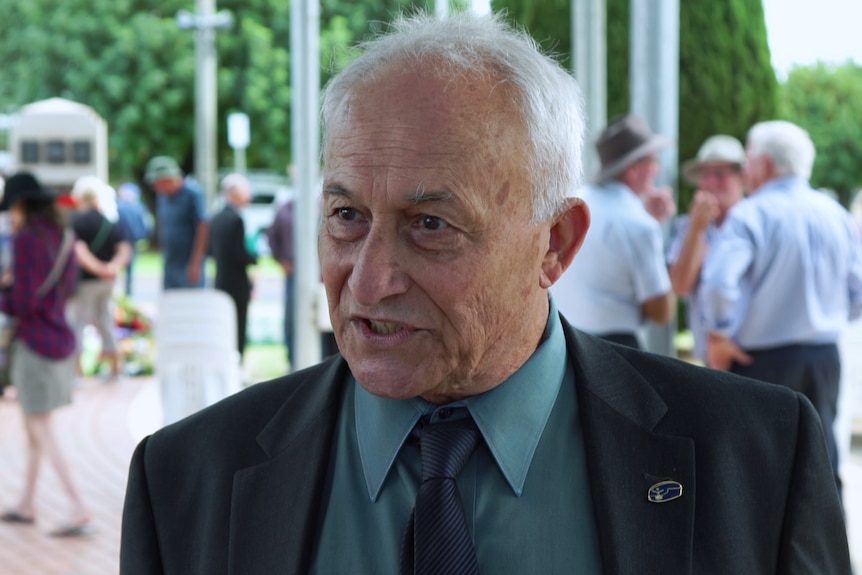 A man in a suit speaks to the camera as a representative of the local town.