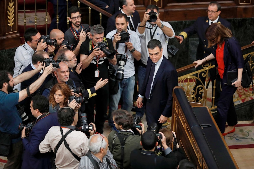 Socialist leader Pedro Sanchez is surrounded by photographers in the parliament