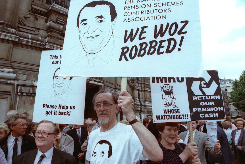 A group of people holding signs with drawngs of Robert Maxwell, march outside an old building.