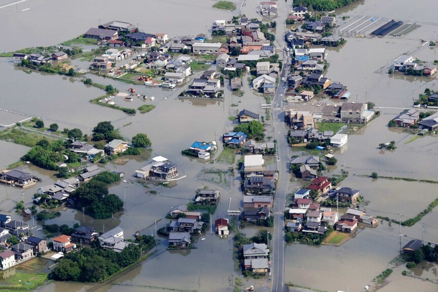 An aerial photo shows a flooded village, which is almost totally inundated except for a major road.