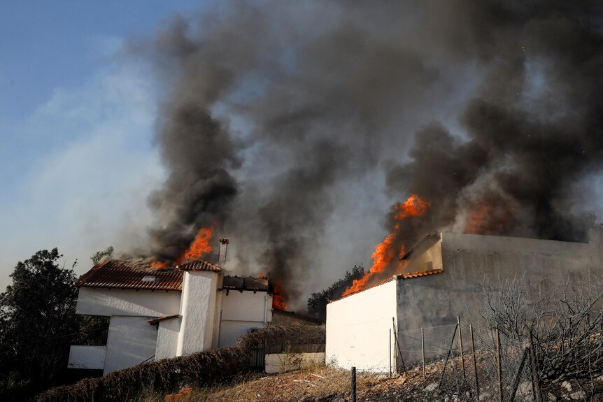 Dwa domy z płomieniami i dymem unoszącym się z dachów. 