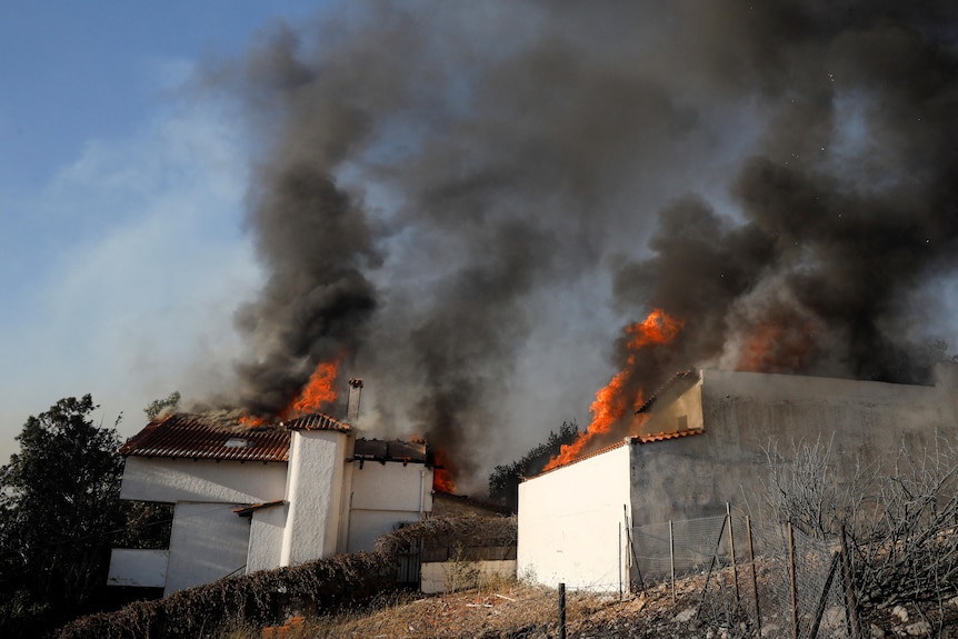 Two houses with flame and smoke coming out of the roofs. 