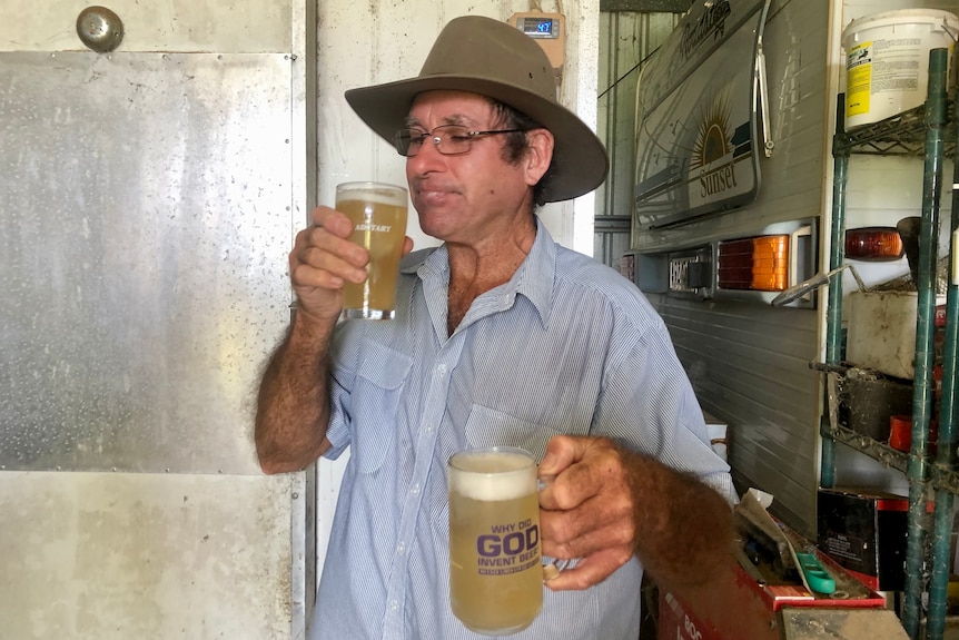 A man enjoys a sip of ginger beer, with another glass mug of ginger beer in his other hand.
