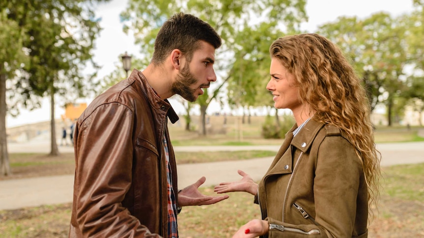 A man and a woman are arguing in a public park.