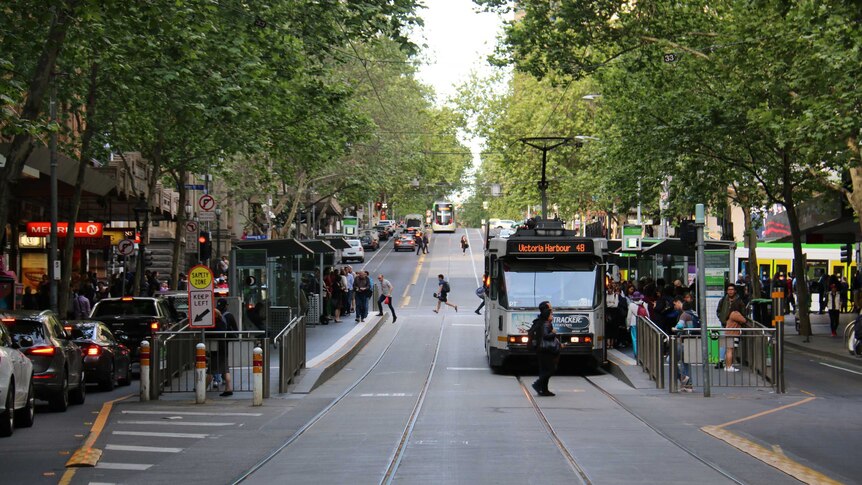 Looking down Collins St at a tram stop near Swanston St.