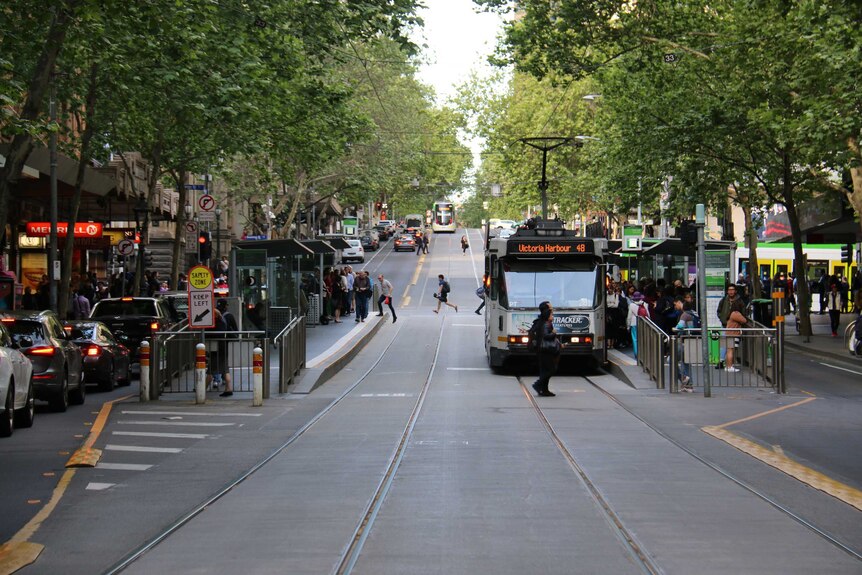 Looking down Collins St at a tram stop near Swanston St.