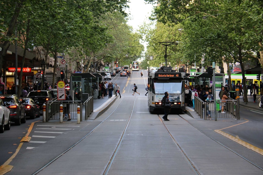 Looking down Collins St at a tram stop near Swanston St.