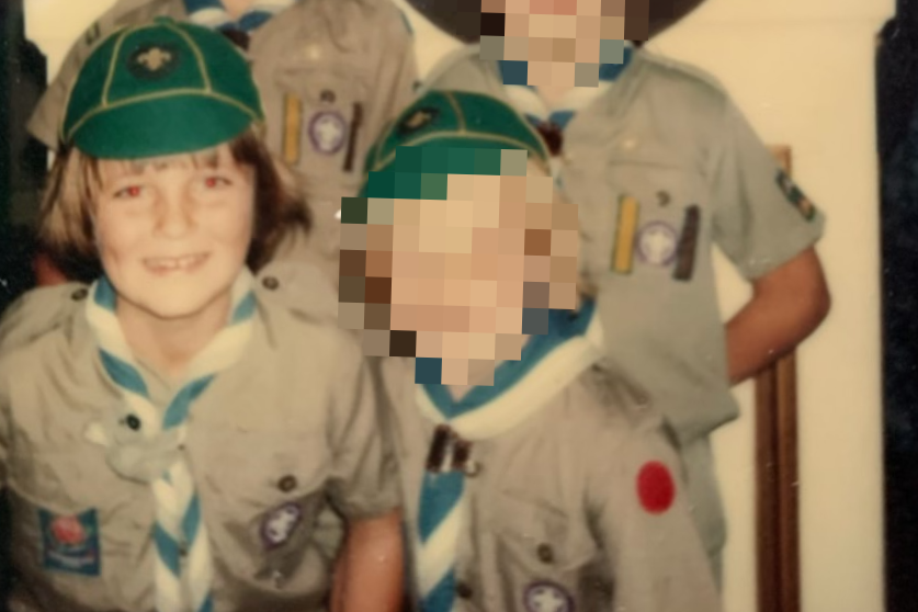 An old, yellowed, image of young boys in scout uniforms. All the faces are pixelated, except one.
