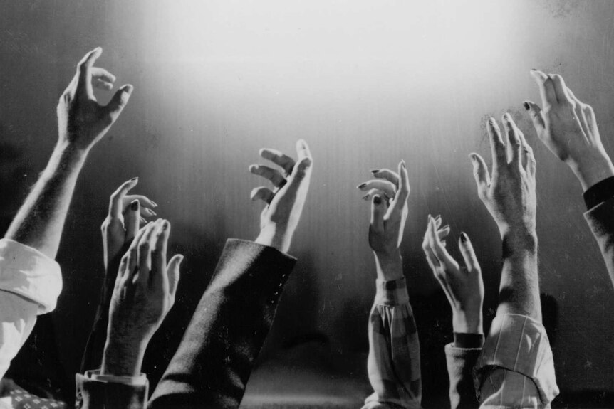 A black and white still from 1987 film Heaven with many arms reaching up