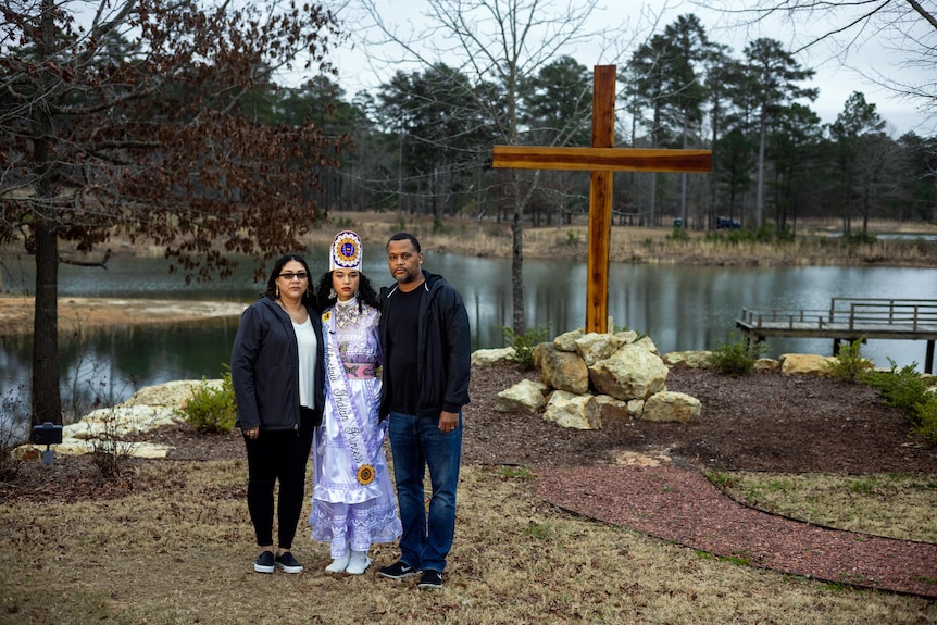 Shemah Crosby (centre) with her parents Lalania Denson and Oga Crosby standing in front of the Lake Pushmataha COVID memorial 