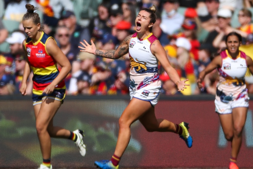 A cheering Brisbane player runs with her arms outstretched. 