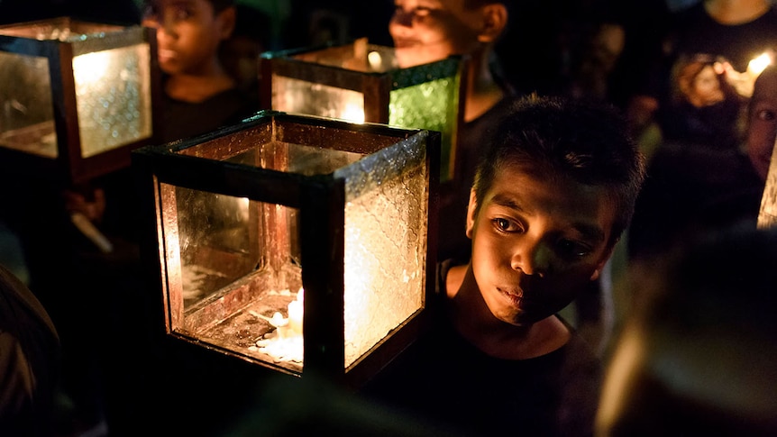 Young boy carries a candle on his shoulder in the procession
