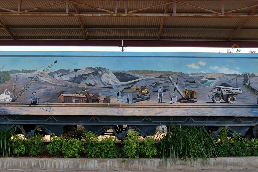 A mural painted on an old train of people working in an old coal mine