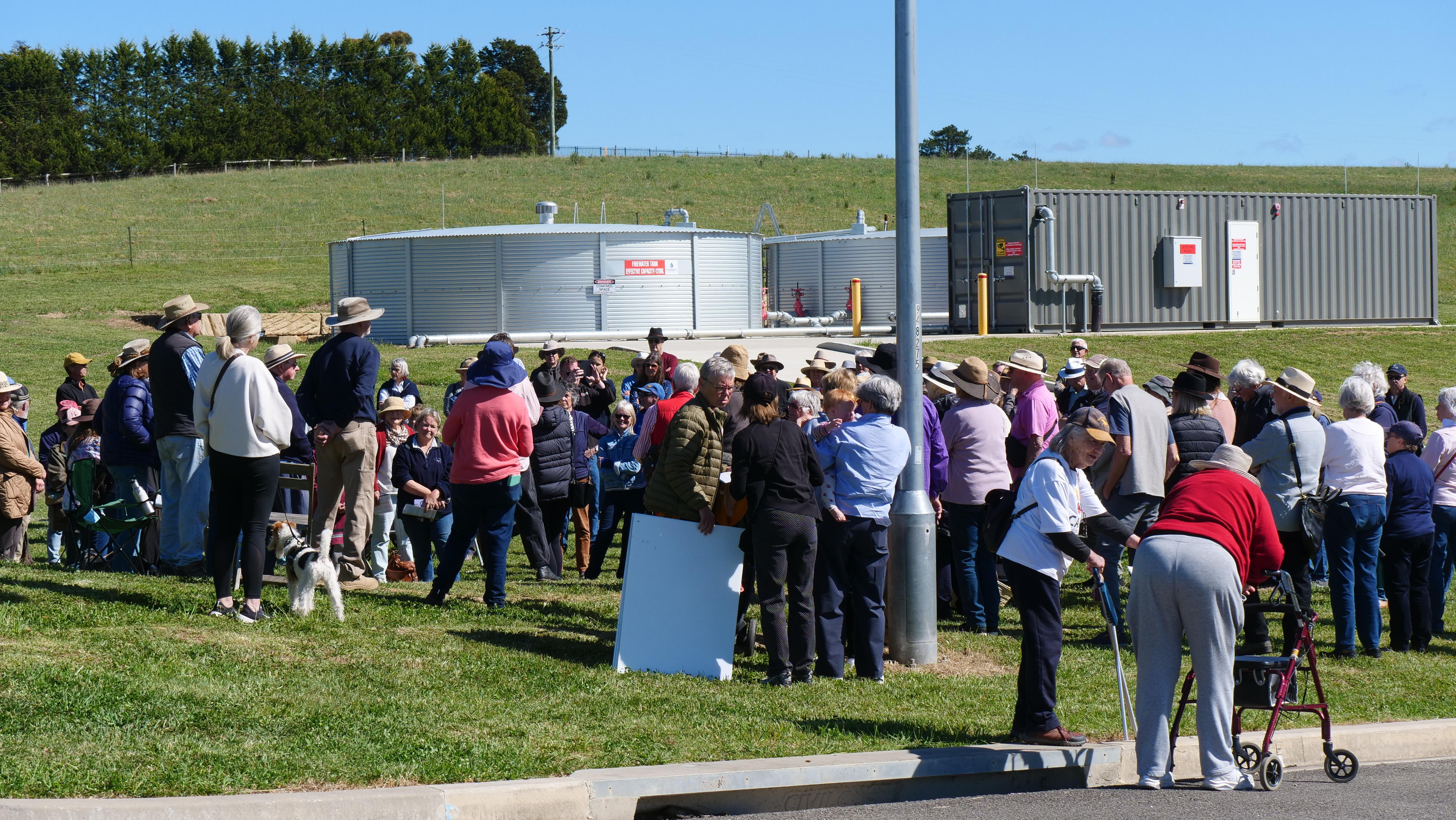 image of a large crowd standing on a green field with a silo in the background