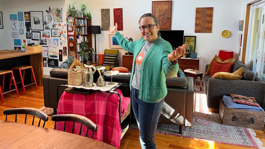 Catherine Krestyn smiles while stnading in front of furniture in her living room.