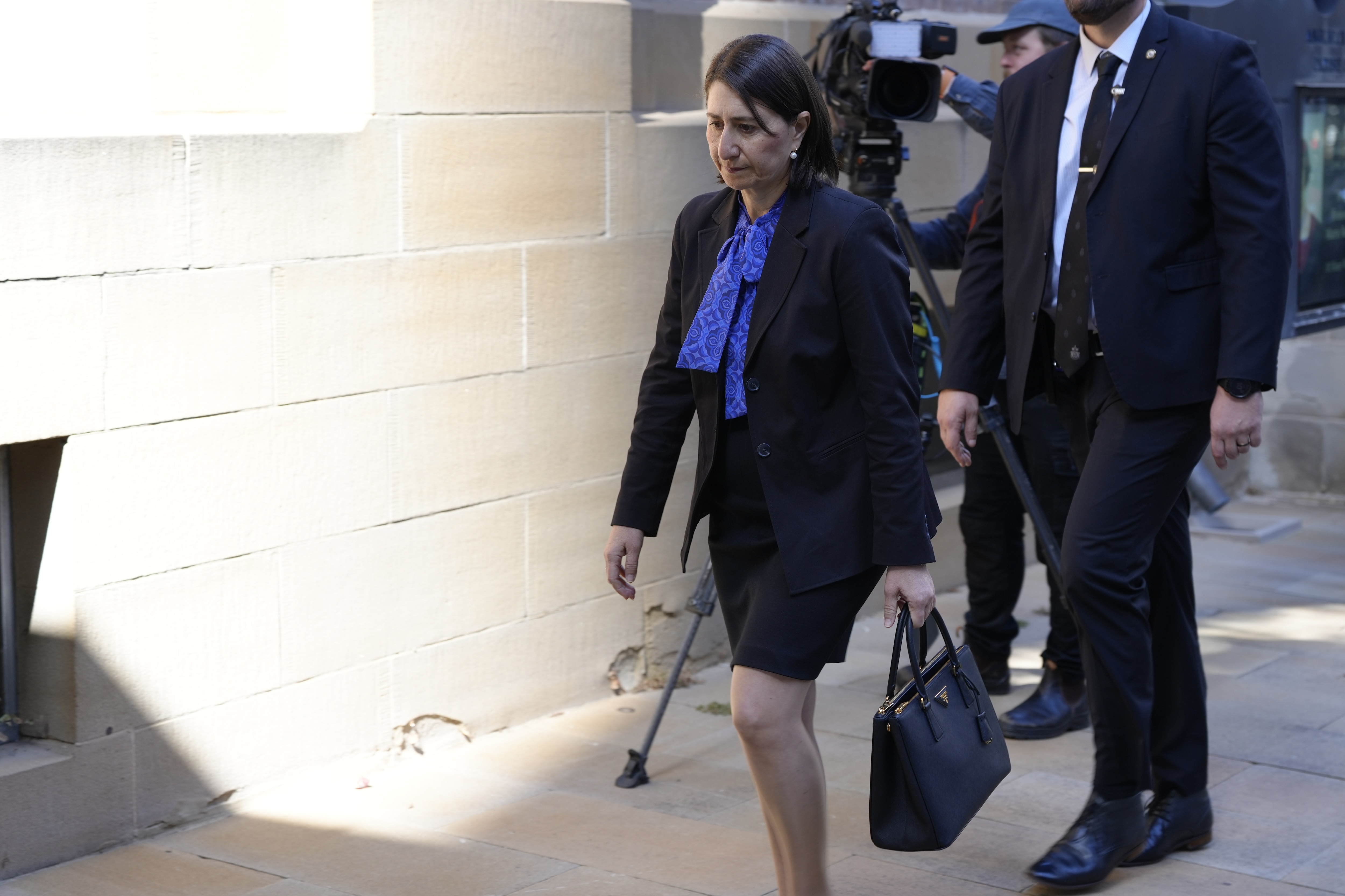 Gladys Berejiklian vestindo um terno preto e carregando uma bolsa preta