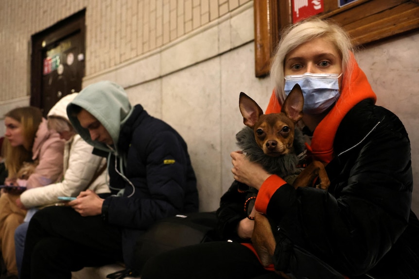 A woman holds her dog as people shelter in a Kyiv metro station