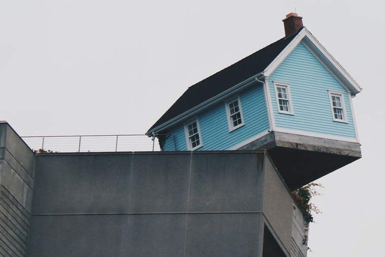 shot of blue weatherboard house teetering on the edge of a building