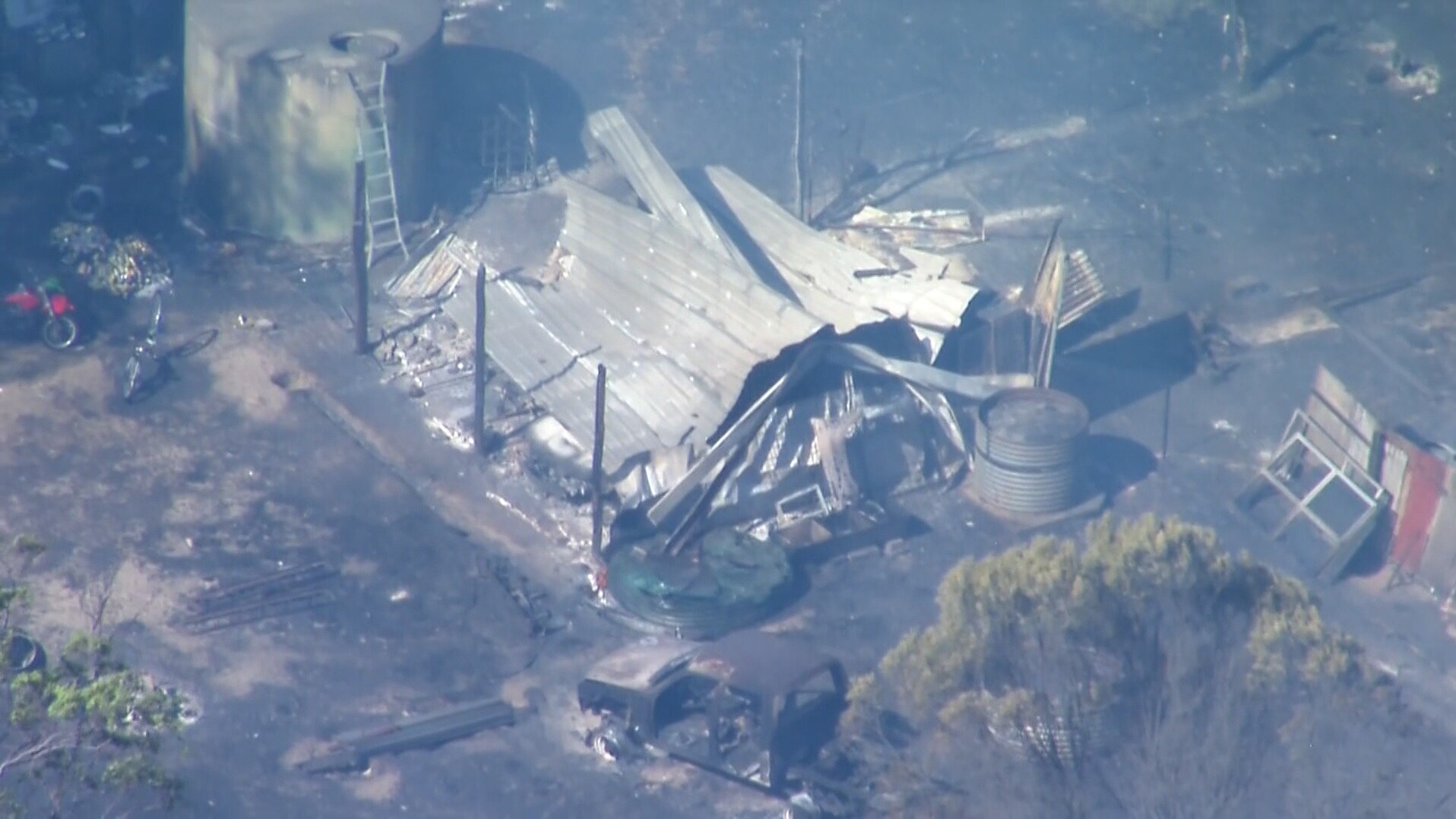A collapsed shed surrounded by burnt out ground