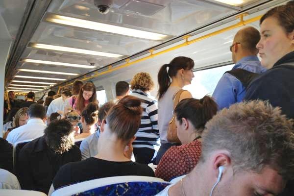 People sitting and standing inside a train carriage.